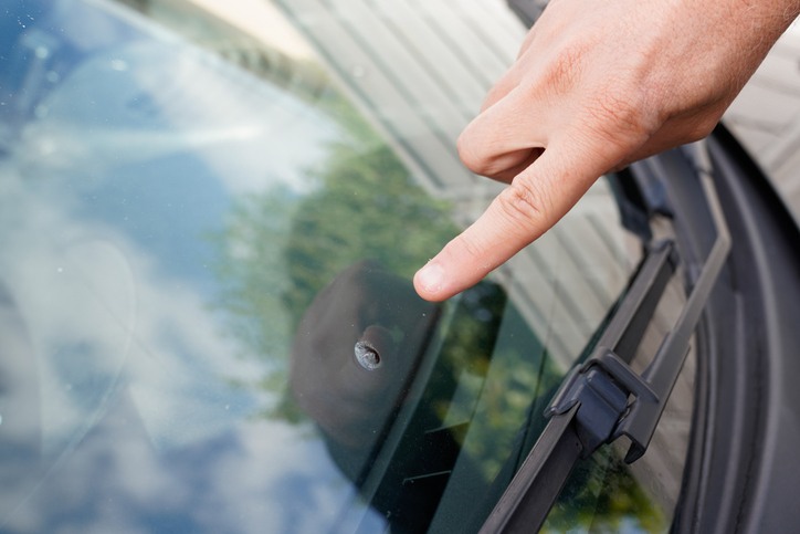 Close-up of a person pointing at chip damage on a car windshield in Edmonton & Leduc