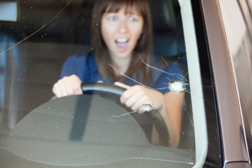 Frightened woman grips the wheel in a car with a cracked windshield in Edmonton & Leduc, AB
