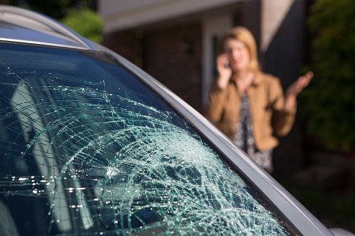 Cracked windshield with concerned woman on phone in background in Edmonton & Leduc, AB